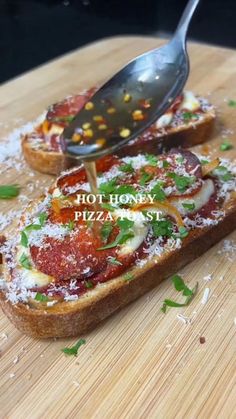 a wooden cutting board topped with slices of bread covered in toppings and a spatula