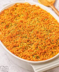 a casserole dish with carrots and parsley in the bottom, next to a wooden spoon