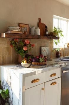 a kitchen with white cabinets and marble counter tops