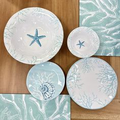 three plates with starfish designs on them sitting on a wooden table next to each other