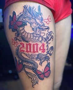 a woman's thigh with a dragon and butterflies tattoo on her leg that reads 2013