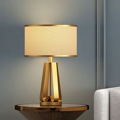 a table with a lamp on it next to a white chair and gray wall in the background