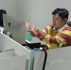 a man sitting in front of a computer desk with his hand up to the screen