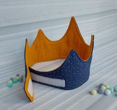 a blue and yellow crown sitting on top of a bed next to candy candies