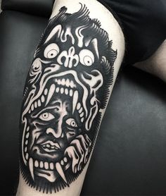 a black and white tattoo on the arm of a man with an evil face in it