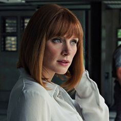 a woman with red hair and blue eyes in a white shirt looking at the camera