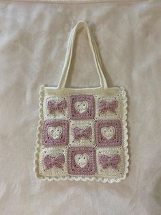 a crocheted bag with teddy bears and bows on the front is laying on a bed