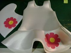 a dress made out of paper with flowers on the front and side, sitting on top of a cutting board