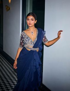 Indulge in ethereal charm with this midnight blue georgette and organza ruffle sari ensemble! Cascading ruffles crafted from georgette and organza create a captivating silhouette. The hand-embroidered v-neck scalloped blouse adds a touch of sophistication, enhanced by tassel detailing at the waist. Complete your look with a matching hand-embroidered belt for added flair. Elegant Blue Pre-draped Saree For Festive Occasions, Bollywood Style Ruffled Organza Pre-draped Saree, Designer Blue Organza Pre-draped Saree, Evening Blue Pre-draped Saree With Sheer Dupatta, Elegant Blue Georgette Lehenga, Blue Organza Pre-draped Saree, Blue Organza Saree For Party Wear, Blue Party Wear Saree In Organza, Blue Georgette Pre-draped Party Saree