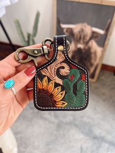 a hand holding a keychain with an image of flowers and plants on it