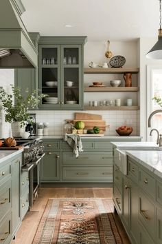 a kitchen filled with lots of green cupboards and counter top space next to a rug