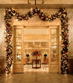 the entrance to a hotel decorated for christmas with lights and garlands on either side