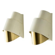 two white and gold wall lights against a white background