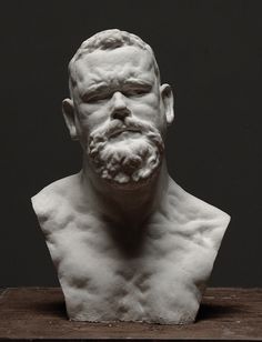 a white sculpture of a man's head on top of a wooden table