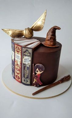 a harry potter themed cake with books and an owl figurine sitting on top