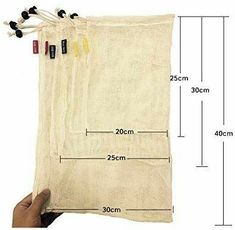 a hand holding a bag with three strings attached to it and measurements for each string