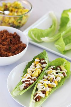 lettuce wraps filled with taco meat and other toppings on white plates