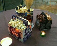 a table topped with two boxes filled with popcorn next to a lit tea light candle