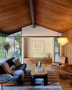 a living room filled with lots of furniture and wooden walls covered in wood paneling