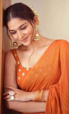 a woman in an orange sari and gold jewelry