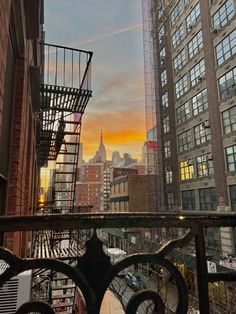 the sun is setting over new york city's skyscrapers as seen from an outdoor balcony