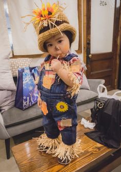 a baby doll is dressed in overalls and a hat with sunflowers on it