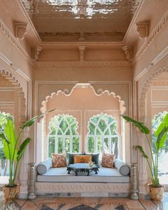 an ornate living room with couches and potted plants