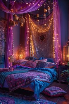 a bed covered in purple and blue sheets with lights hanging from the ceiling above it