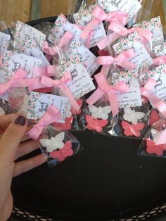 there are many small pink and white bows in the bag with name tags on them