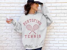 Vintage-inspired Portofino tennis sweatshirt. Playing tennis in Italy, especially near the coast, is a different kind of magic. We love how this old-money aesthetic tennis sweatshirt turned out. The graphic is distressed to give that vintage vibe. Q U I C K * F A C T S * - Gildan 18000 Sweatshirt - 50% cotton and 50% polyester - Medium-heavy (8.0 oz/yd² (271.25 g/m. - Wash and dry normally (on cool for best results ) - OEKO-TEX certified low-impact dyes - US Cotton Trust Protocol member * F I T Graphic Print Long Sleeve Sweatshirt For Tennis, Graphic Print Long Sleeve Tennis Sweatshirt, Long Sleeve Graphic Sweatshirt For Tennis, Long Sleeve Graphic Print Sweatshirt For Tennis, Casual Relaxed Fit Sweatshirt For Tennis, Long Sleeve Graphic Print Tennis Tops, Long Sleeve Graphic Print Tops For Tennis, Long Sleeve Relaxed Fit Sweatshirt For Tennis, Aesthetic Tennis