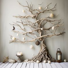 a tree made out of branches with ornaments hanging from it's branches and on the wall