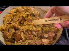 a person is holding a wooden spoon over some food in a pan on the stove