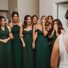 a group of women standing next to each other in front of a mirror wearing green dresses