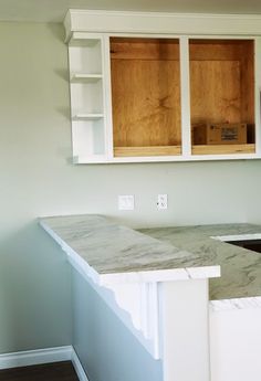 an empty kitchen with white cabinets and marble counter tops