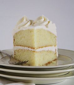 a slice of white cake sitting on top of two plates with silverware next to it