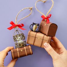 two handmade gift boxes are being held by someone's hands on a purple background