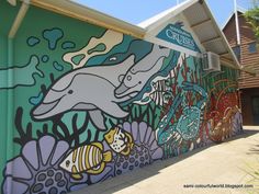 a mural on the side of a building with dolphins and other marine creatures painted on it