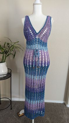 The "Ocean Twilight Dress" is a stunning handmade crochet piece that features a delicate mesh pattern, perfect for beachwear or summer outings. Its variegated hues transition smoothly from deep purples to serene blues, creating a captivating ombré effect reminiscent of a twilight sky over the ocean. The dress boasts a flattering V-neckline and adjustable tie at the waist, accentuating the figure while maintaining an airy, bohemian charm. This versatile and elegant dress is a unique blend of artistry and comfort, ideal for those seeking a stylish yet relaxed look. CUSTOM MADE ORDER: Choose the color, size, and material for a unique product. Experience the perfect combination of style and functionality with custom options tailored to your liking. Blue Bohemian Crochet Dress For Beach, Blue Bohemian Crochet Beach Dress, Blue Crochet Dress For Beach Cover-up, Multicolor Beachy Crochet Dress For The Beach, Fitted Blue Crochet Dress For Beach, Fitted Blue Crochet Dress For The Beach, Blue Crochet Summer Dress For Beach, Blue Crochet Summer Dress For Beach Season, Blue Summer Crochet Dress For Beach