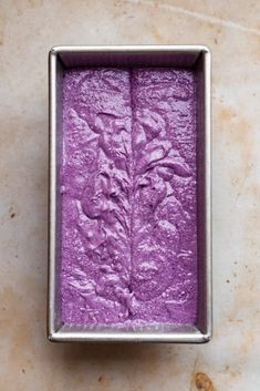 a square metal container filled with purple food