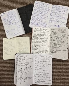 four notebooks with writing on them sitting next to each other