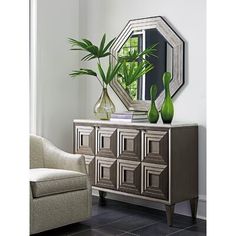 a living room with a chair, mirror and plant on the sideboard in front of it