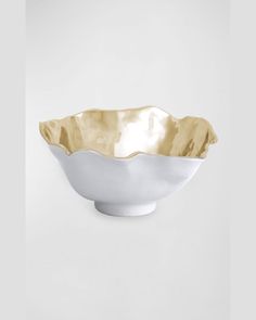 a white and gold bowl sitting on top of a table next to a gray wall