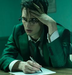 a man sitting at a table with a pen and paper in front of his face