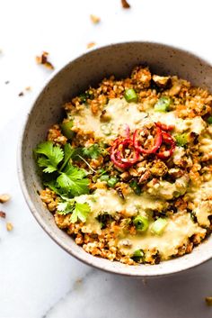 a white bowl filled with food and garnished with cilantro, red peppers