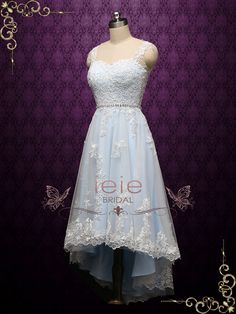 a white dress on display in front of a purple wall with butterflies and laces