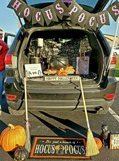 the back of a car with halloween decorations and brooms in it's trunk