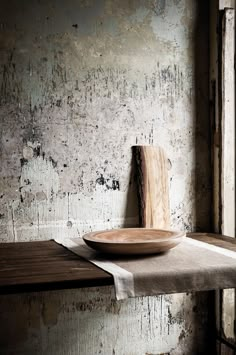 a wooden plate sitting on top of a table next to a wall with peeling paint