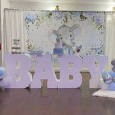 there is a baby sign and balloons in front of the table with an elephant on it