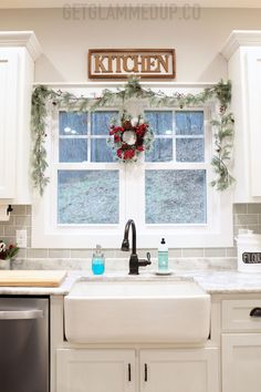 a kitchen decorated for christmas with wreaths on the window sill, sink and dishwasher