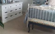 a bed room with a neatly made bed next to a white dresser and chest of drawers